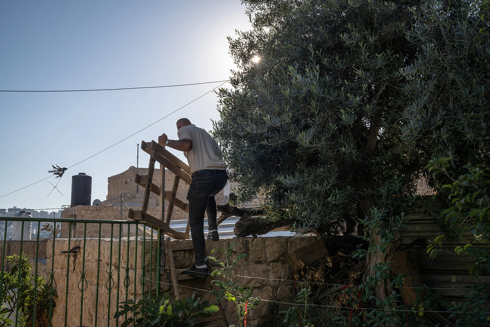 Aref Jaber climbs onto the roof of a neighbor's home to get to the street in the Jaber neighborhood in Hebron.